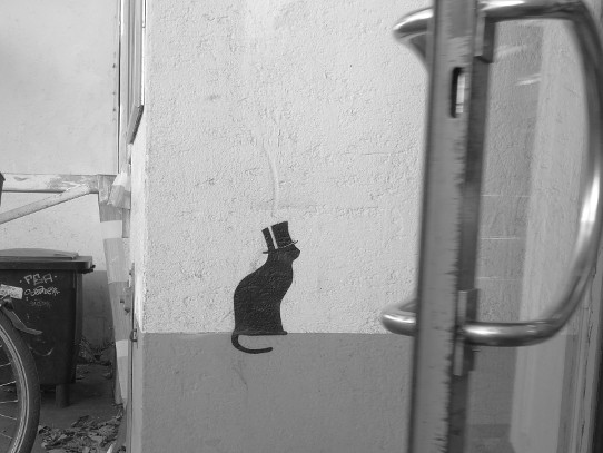 Graffiti: Katze mit Zylinder am Eingang eines Disconters