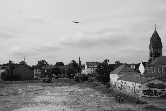 Blick vom höchsten Punkt des Lärmschutzwalls der Brache am Ende der Godehardstraße in Bremen, Hemelingen, auf einen Teil der Diedrich-Wilkens-Straße und das Ende der Godehardstraße mit der Godehard-Kirche
