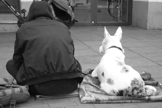Ein Bettler sitzt auf dem Bürgersteig