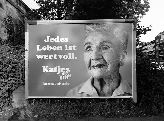 Plakat mit Foto einer alten Frau, die leicht lächelt